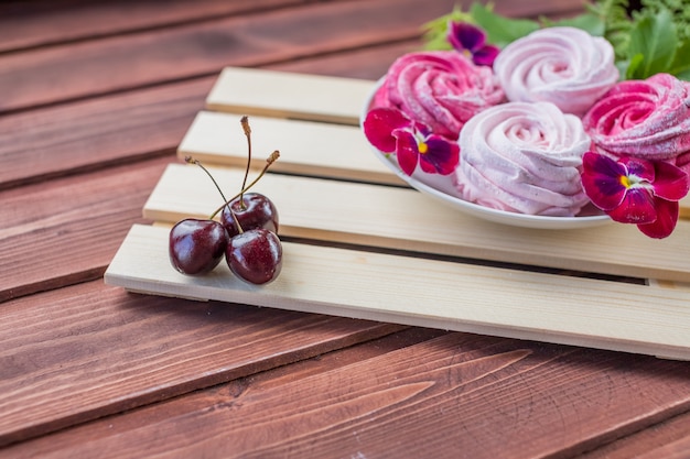 Eibisch mit Kirschbeere und Blumen auf hellem hölzernem Hintergrund