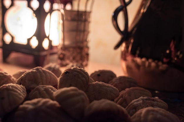 Eid kahk árabe con cafetera en la mesa con poca luz amarilla