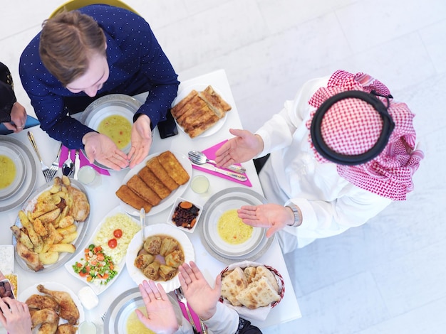 Eid Mubarak Musulmanes rezando antes de la cena iftar. Comer comida tradicional durante el mes de fiesta del Ramadán en casa. La comida y bebida halal islámica en la familia islámica occidental moderna