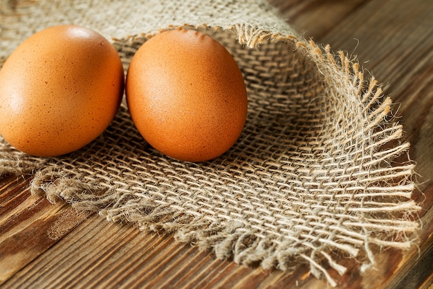 Eier auf Sackleinen über hölzernem Hintergrund