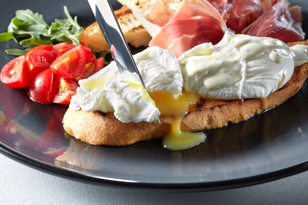 Eier Benedict auf geröstetem Brot mit Schinken, Tomaten und Sauce