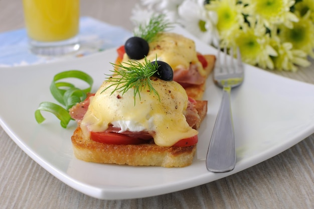 Eier Benedict mit Schinken und Tomate auf Toast mit Käse