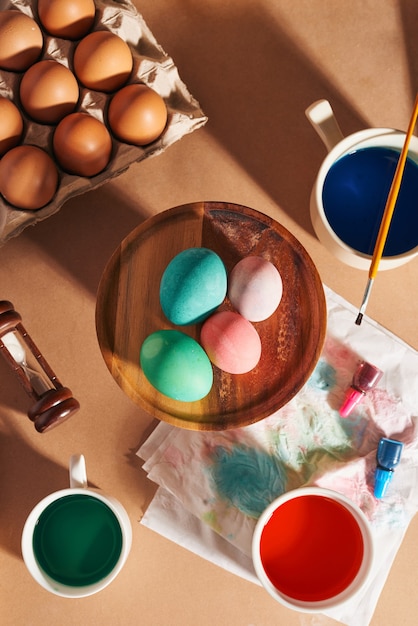 Eier, bunte Farben, Pinsel, Bleistifte auf Holzuntergrund, Eier färben, Vorbereitung auf Ostern, saisonale Frühlingsferien