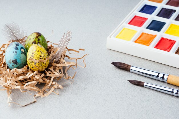 Eier färben für Ostern. Farben, Pinsel, Wachteleier auf grauem Hintergrund. Vorbereitung für die Feier von Ostern, traditionelle Dekorationen, Hintergrund. Kreatives Konzept.