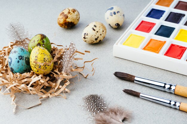 Eier färben für Ostern. Farben, Pinsel, Wachteleier auf grauem Hintergrund. Vorbereitung für die Feier von Ostern, traditionelle Dekorationen, Hintergrund. Kreatives Konzept.