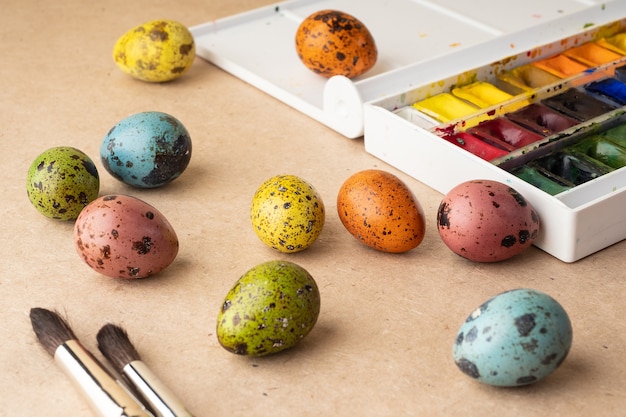 Eier färben für Ostern. Farben, Pinsel, Wachteleier auf handwerklichem Hintergrund. Vorbereitung für die Feier von Ostern, Dekorationen für den Urlaub, Hintergrund. Kreatives Konzept.
