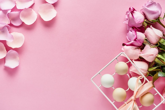 Eier im weißen Keramikhalter und in den Blumen auf rosa Hintergrund. Draufsicht.