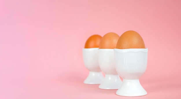 Foto eier in eierbechern auf rosafarbenem hintergrund osterkomposition mit kopierraum