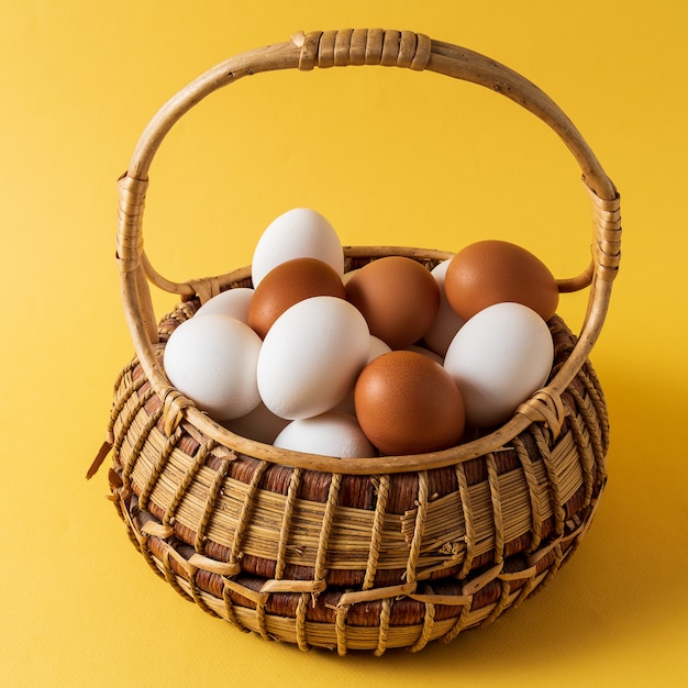 Eier in einem Korb über gelbem Hintergrund.