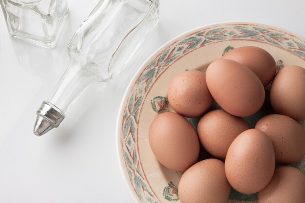 Eier in Teller mit Flasche auf weißem Hintergrund