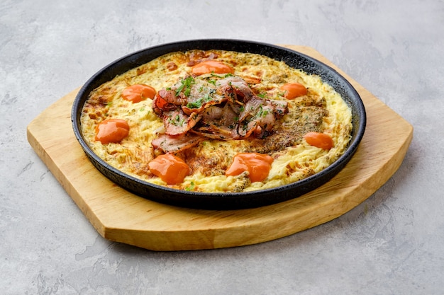 Eier mit Speck und Tomaten im Ofen in einer gusseisernen Pfanne gebacken