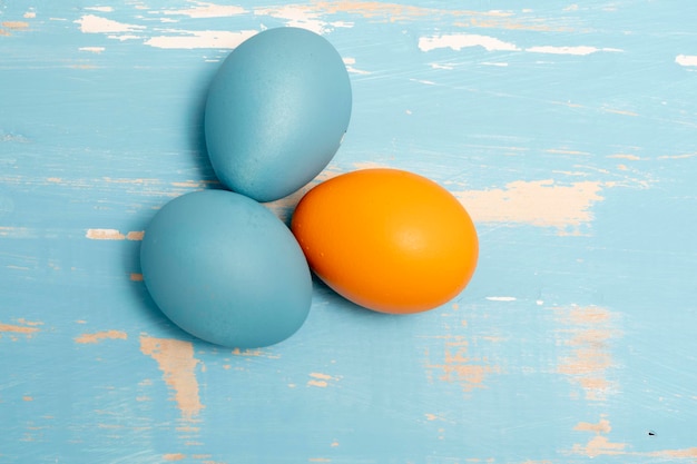 Eier symbolisieren die Osterferien in blauer und oranger Farbe auf einem Hintergrund aus gealtertem Holz