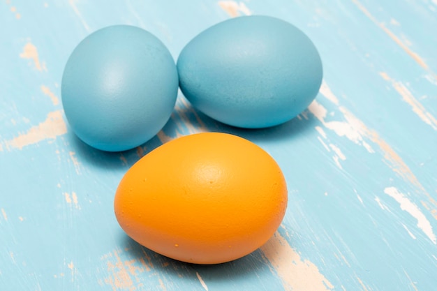 Eier symbolisieren die Osterferien in blauer und oranger Farbe auf einem Hintergrund aus gealtertem Holz