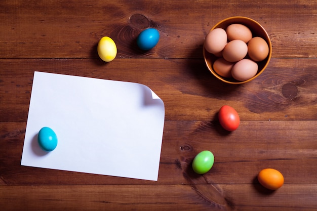 Eier und leeres weißes Papier auf braunem Holztisch