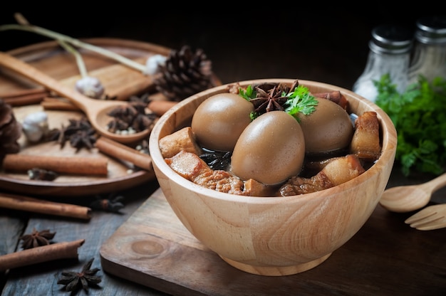 Eier und Schweinefleisch kochten in der Soße auf Holztisch.