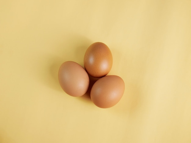 Eier werden in Gruppen von drei Eierschalen mit unterschiedlichen Mustern gelegt. Aufnahme in einem Studio mit Licht und Schatten vor einem eierschalenfarbenen Hintergrund