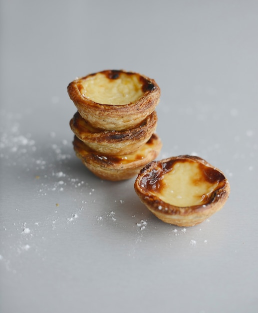 Eierkuchen traditionelles portugiesisches Dessert Pastel de Nata Pasteis auf einem Teller Grauer Steinhintergrund