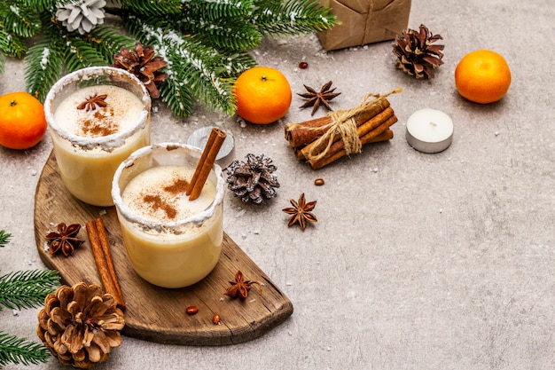 Eierlikör mit Zimt und Muskatnuss zu Weihnachten und in den Winterferien. Selbst gemachtes Getränk in Gläsern mit würzigem Rand. Mandarinen, Kerzen, Geschenk.