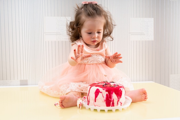Eifriges kleines Mädchen, das genießt, ihren Geburtstagskuchen zu essen, der gekrönt wird