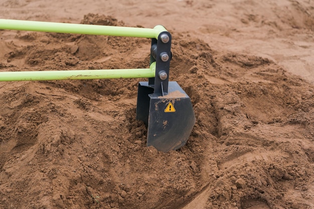 Eimer eines Spielzeugbaggers im Sandkasten auf dem Spielplatz