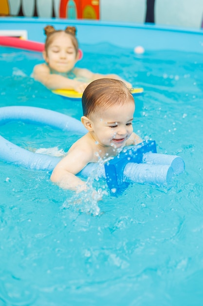 Ein 2-jähriger kleiner Junge lernt mit einem Trainer in einem Pool schwimmen Schwimmunterricht für Kinder