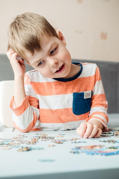 Ein 6-jähriger Junge sammelt zu Hause ein Puzzle und hält seinen Kopf. Entwicklung der Feinmotorik und des Gehirns