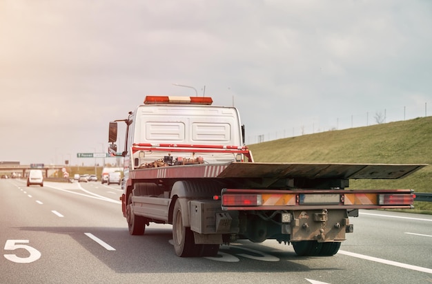 Ein Abschleppwagen mit rotem Licht auf der Rückseite fährt eine Autobahn entlang.