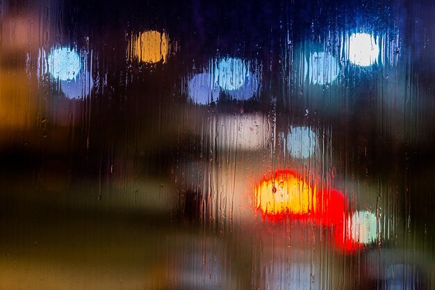 Ein abstrakter Hintergrund Nachtstraßenlaternen Bokeh durch nasses Glas Nahaufnahme mit selektivem Fokus