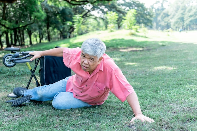 Ein älterer asiatischer Mann, der auf dem grünen Rasen liegt, ist ein Patient mit Osteoarthritis