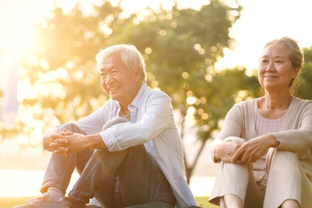 Foto ein älterer asiatischer mann und eine asiatische frau genießen den sonnenuntergang im park