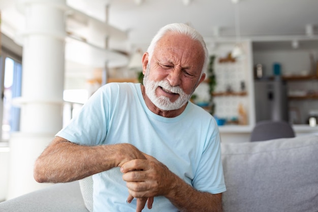 Foto ein älterer mann hat schmerzen in fingern und händen, ein alter mann mit schmerzen in den fingern, ein mann massiert seine arthritische hand und sein handgelenk.