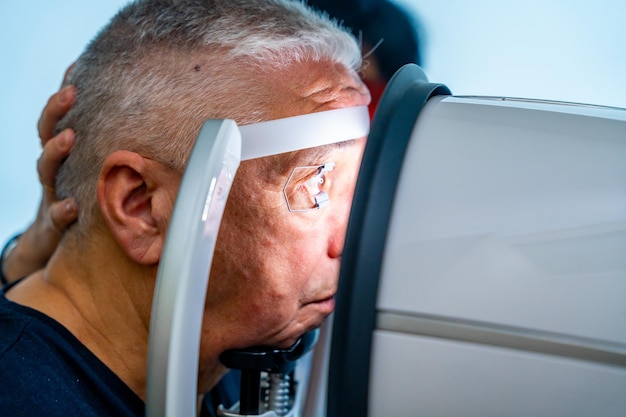 Ein älterer Mann lehnt den Kopf auf den Scanner, um Glaukom zu überprüfen
