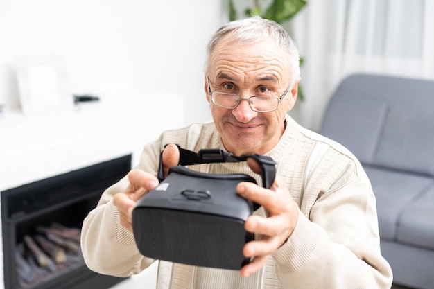 Ein älterer Mann spielt Video-Fußballspiel mit Virtual-Reality-Brille und Joystick, Hi-Tech-Konzept mit vr-Brille