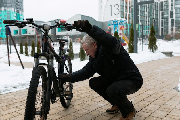 Ein älterer Mann überprüft sein Fahrrad auf der Straße