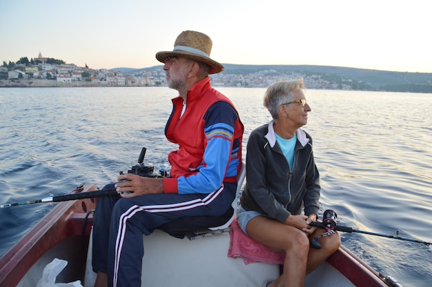Foto ein älterer mann und eine ältere frau sitzen auf einem boot im fluss gegen den himmel