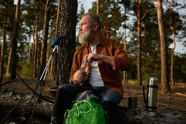 Foto ein älterer wanderer macht eine pause beim wandern im kiefernwald