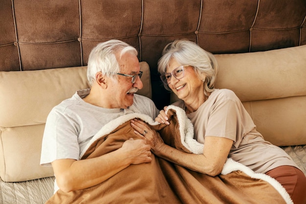 Ein älteres Paar verbringt morgens romantische Momente im Bett.