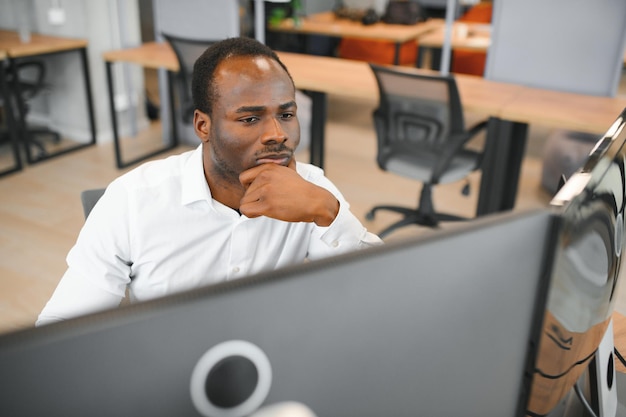 Ein afrikanisch-amerikanischer Händler arbeitet am Computer mit angezeigten Echtzeit-Aktien