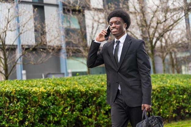 Ein afrikanischer Geschäftsmann geht mit dem Telefon durch die Straße