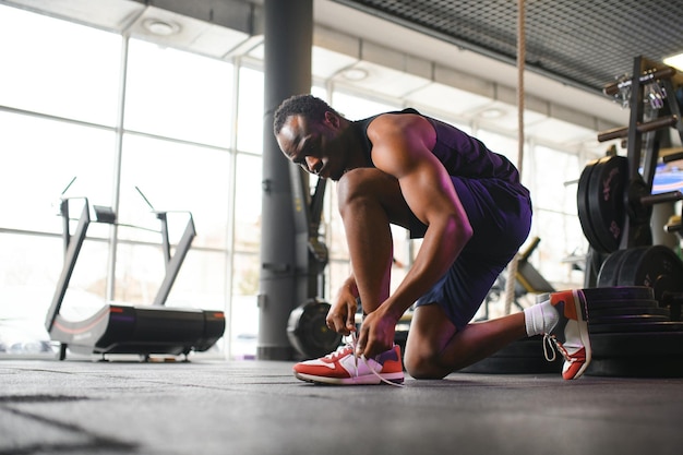 Foto ein afrikanischer mann bindet schnürsenkel an sneaker im fitnessstudio