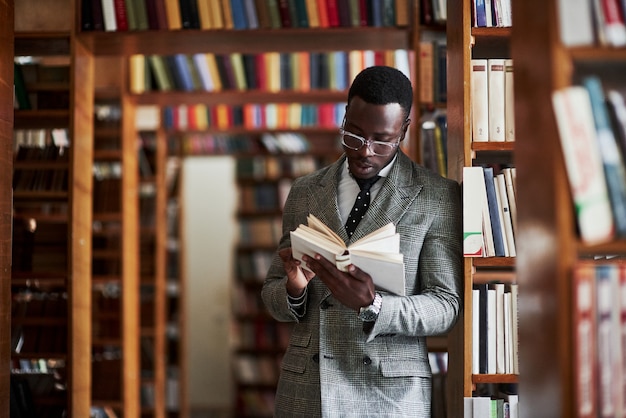 Ein Afroamerikaner in einem Geschäftsanzug, der in einer Bibliothek steht