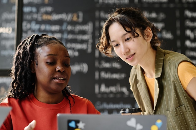 Ein afroamerikanischer Lehrer benutzt einen Laptop, um dem Schüler während des Unterrichts im Klassenzimmer Material zu erklären