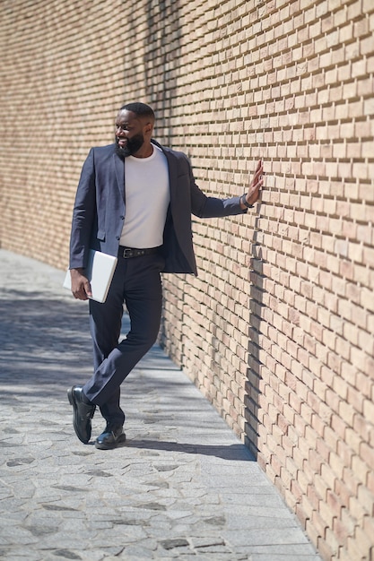 Ein afroamerikanischer Mann in einem Anzug, der in der Nähe der Mauer steht