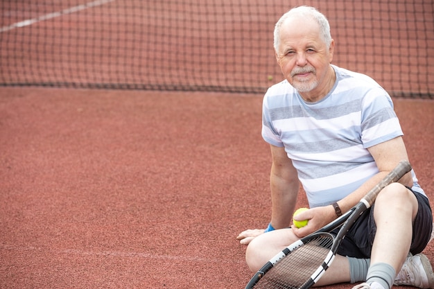 Ein aktiver Rentner, Porträt eines älteren Mannes, der draußen Tennis spielt, Sport im Ruhestand, Sportkonzept