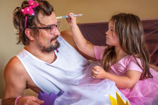 Ein als Prinzessin verkleidetes Mädchen schmückt Papa. Spiele für Mädchen mit Papa