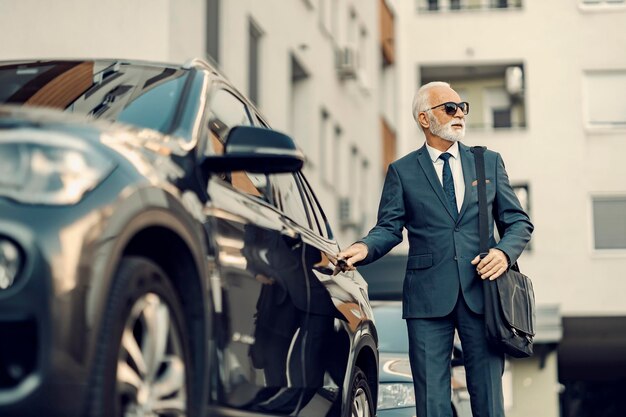 Ein alter Geschäftsmann öffnet sein Auto