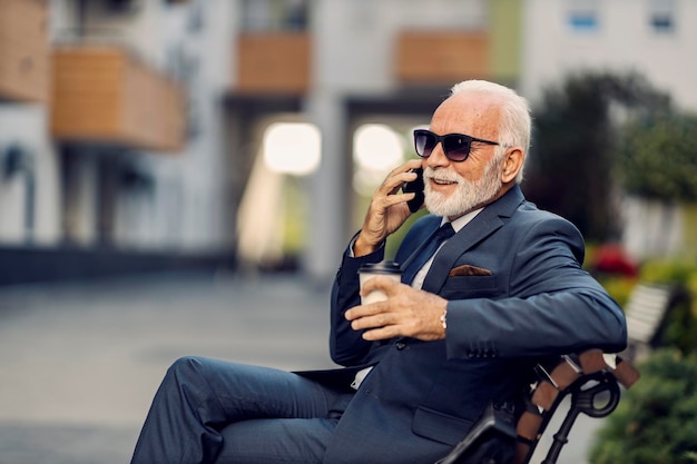 Ein alter Geschäftsmann telefoniert in seiner Kaffeepause