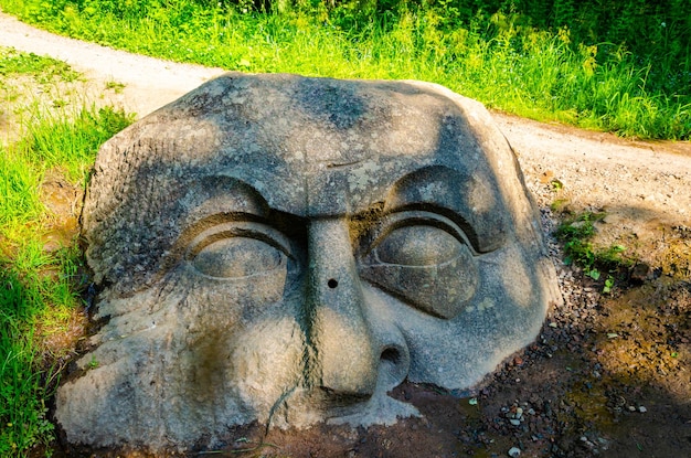 Foto ein alter granitskulpturkopf im boden.