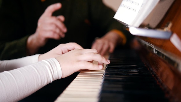 Ein alter Lehrer, der einem kleinen Mädchen beibringt, wie man Klavier spielt