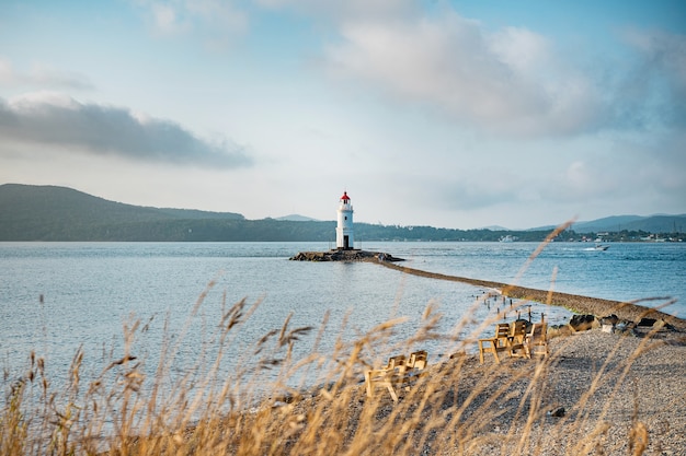 Ein alter Leuchtturm mit rotem Dach an der Küste. Meereslandschaft. Postkarte von der Reise.